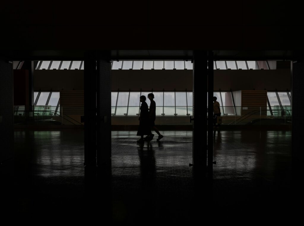 Silhouette of people walking through a modern hallway with large windows in Shanghai, China.